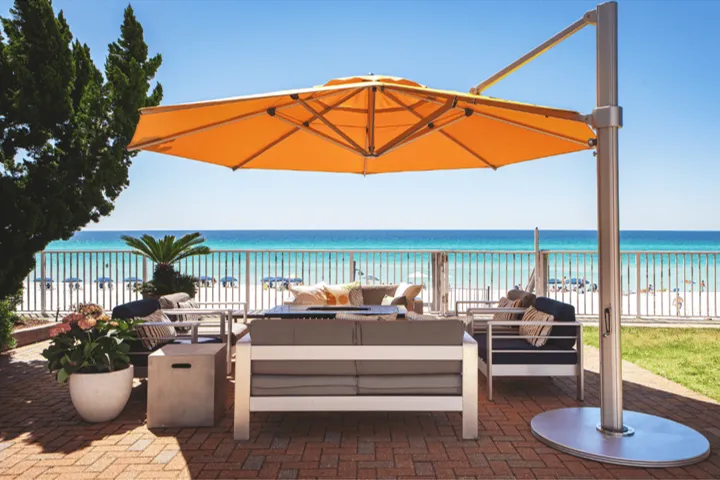 Large cantilever umbrella shading outdoor seating in a waterfront hospitality setting with wide coverage area